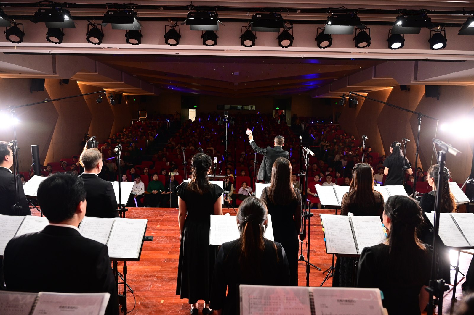 A view from behind the accompanist towards the conductor and choir on stage